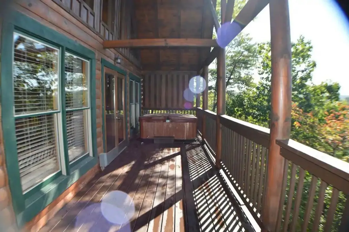 A private outdoor hot tub on a wooden deck, surrounded by trees and greenery, with a wooden railing providing both comfort and seclusion. The tranquil setting highlights relaxation, privacy, and immersion in nature, with the hot tub as the focal point.